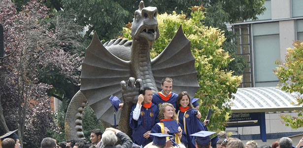 Photo of graduating students in front of Dragon Park Statue